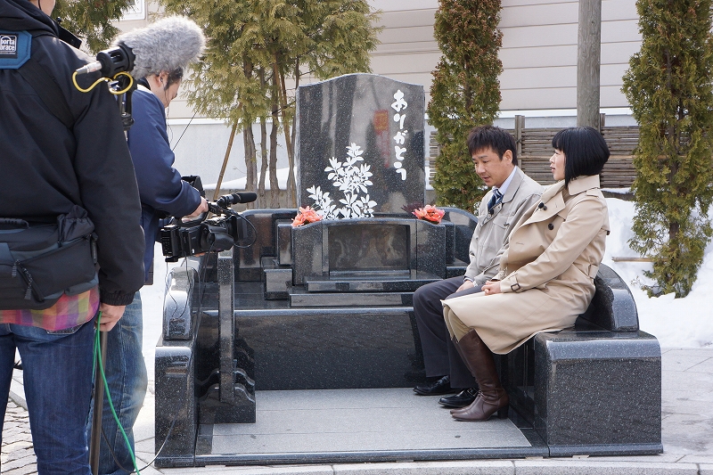 お墓の上で石井雅子さんから取材を受けています。